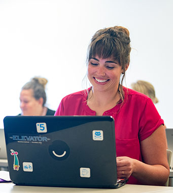 带着笔记本电脑微笑的女计算机科学专业学生。