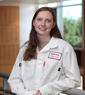 哥伦布州立大学的学生埃里卡·米勒倚在栏杆上，穿着本田的制服微笑着。