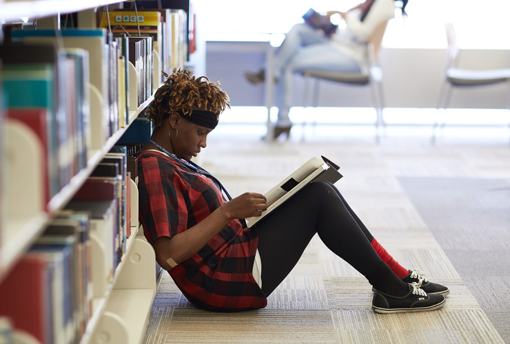 学生坐在图书馆地板上看书。
